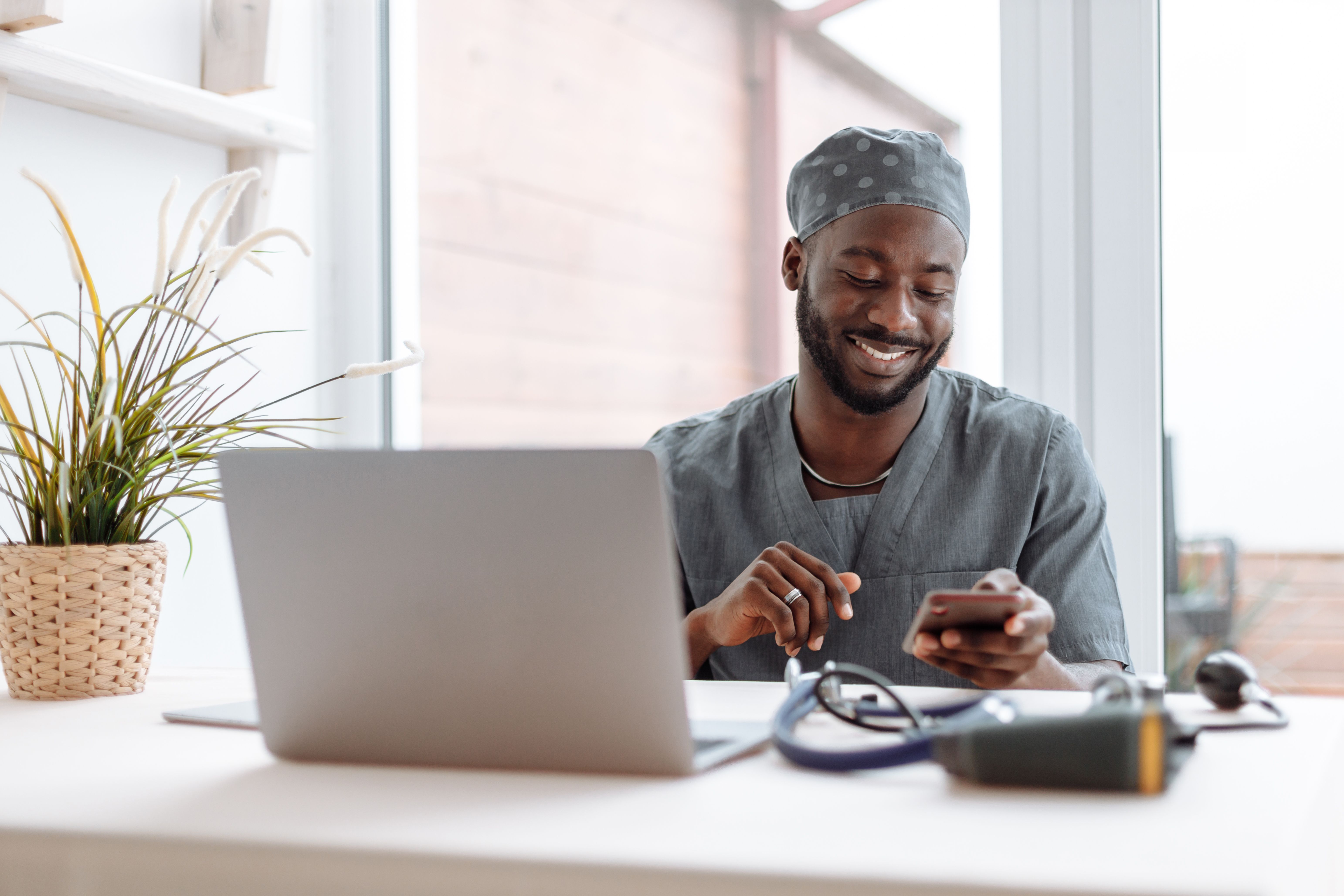 Clinician reviewing patient information on a phone and laptop